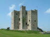 Trim Castle - a solid stone castle, 3 storeys high, small windows,  blue sky and grass